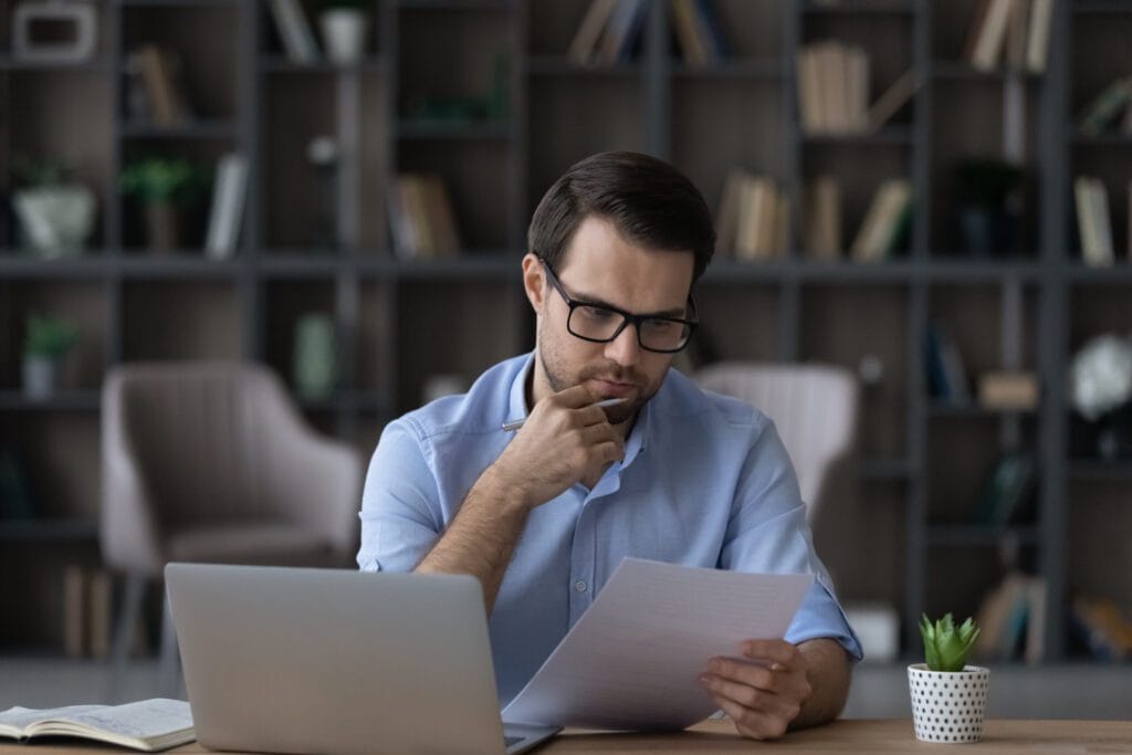 homem olhando papel e computador