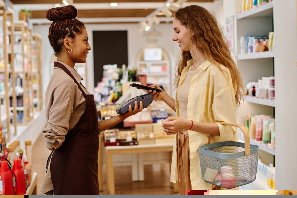 vendedora em uma loja apresentando a maquininha de cartão a uma cliente