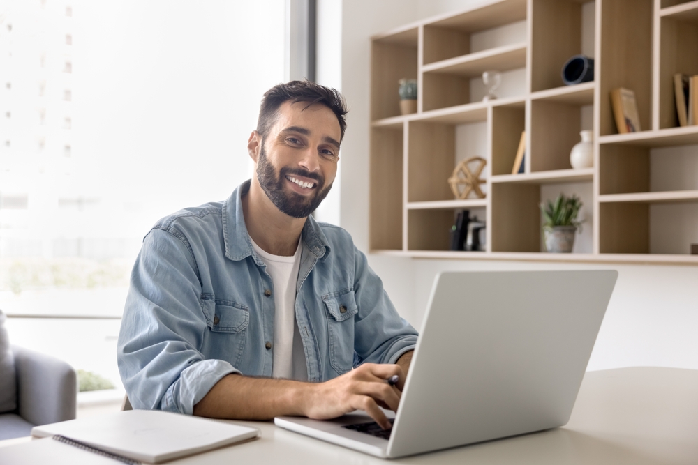 empresário sentado de frente ao notebook e sorrindo