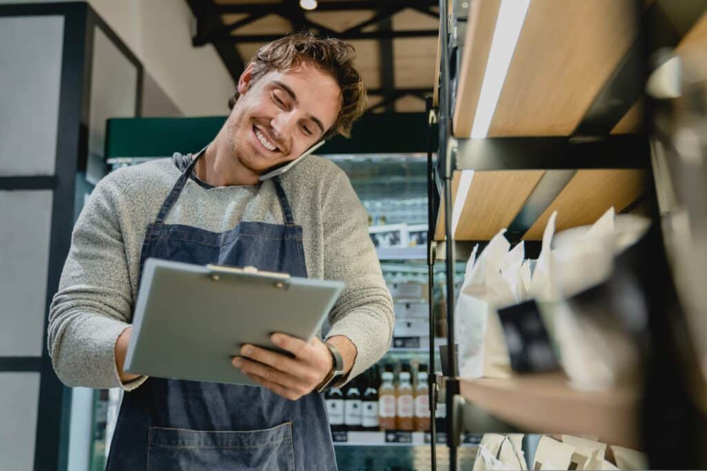 dono de loja falando ao celular com um tablet na mão