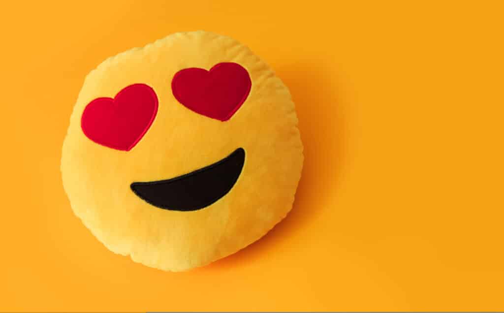 Emoji de sorriso e olhos em forma de coração posicionado em um fundo amarelo
