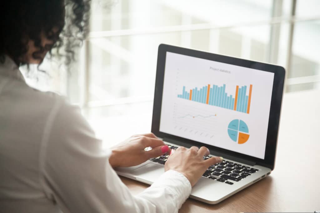 empresária sentada à mesa na frente no notebook com alguns gráficos na tela