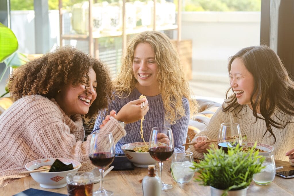 mulheres em um restaurante comendo e sorrindo