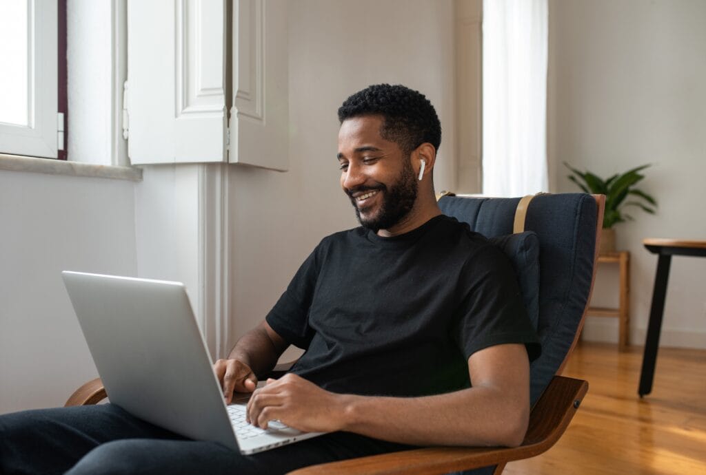 empresário sentado com notebook, digitando e sorrindo