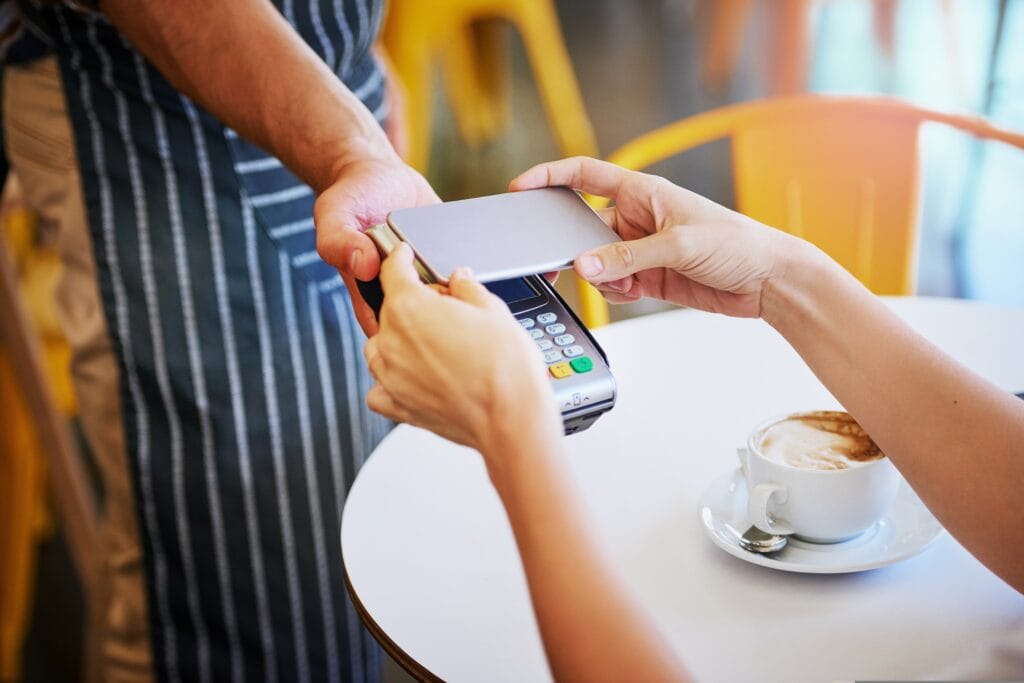 atendente de restaurante oferecendo a maquininha para o cliente pagar por aproximação