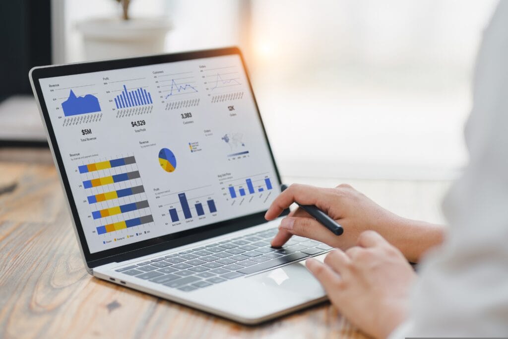 pessoa digitando em um notebook em cuja tela está um painel com gráficos financeiros