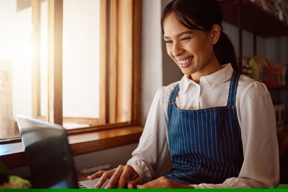 dono de loja de café, cafeteria, sentado na frente no notebook sorrindo