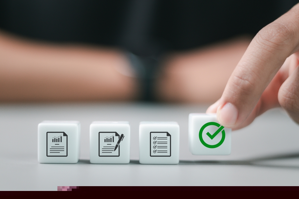 mãos de uma pessoa alinhando pequenos dados com ícones de processos e de check positivo, conferido no último