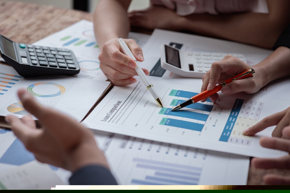 pessoas analisando gráficos financeiros sobre uma mesa